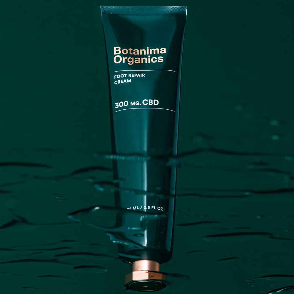 Foot-Repair-CBD-Cream-Tube-on-Green-Background-With-Water-Effect-Botanima-Organics-Premium-Skincare