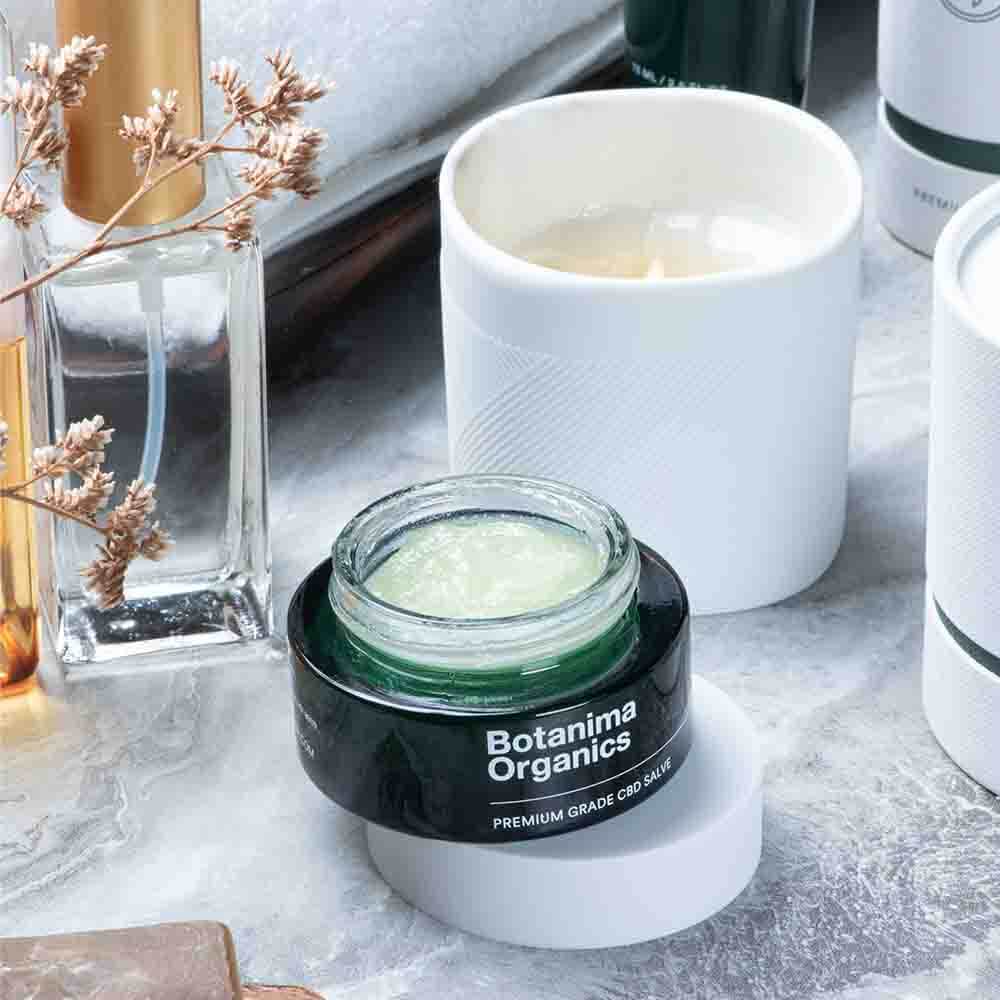 Premium-Green-CBD-Salve-Jar-With-a-Candle-in-a-Bathroom-Botanima-Organics