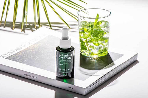 Premium-CBD-Oil-Tincture-Next-to-A-Glass-of-Water-on-A-Book-Lifestyle